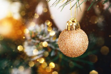 Bulanık ışıklı süslemeli Noel ağacındaki altın top bokeh. Seçici odaklanma. Yılbaşı arifesi için süslemeli tatil kartı.