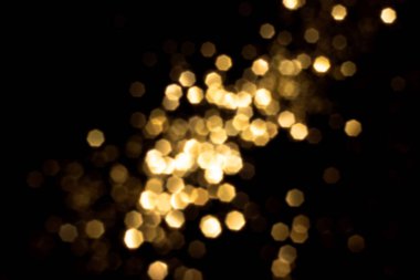 Siyah arka planda altın bulanık bokeh ışıkları. Kutlamak için ışıldayan yıldızlar