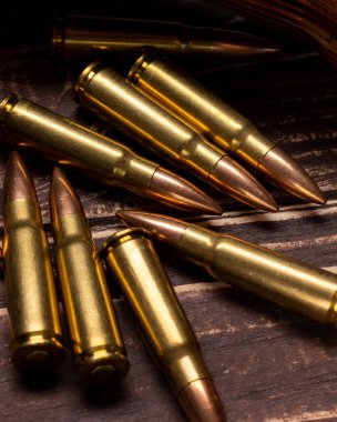 Koyu renk ahşap arka planda pirinç ve bakır tüfek mermileri. Çarpıcı ışıklandırmalı cephane..