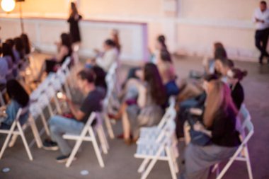 İnsanlar klasik müzik konseri izliyorlar. Bulanık genç ve yetişkin kadınlar, erkekler ve diğer insanlar klasik orkestranın konserini açık havada dinliyorlardı..