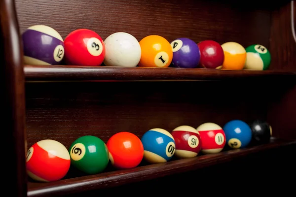 Balls for pool billiards on the shelf , billiard balls for American billiards , balls for Russian billiards , colored or white balls for billiards on a wooden background. Close-up photo. Soft focus.