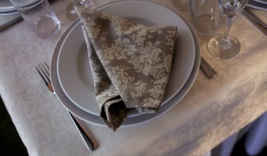 Masanın klasik tasarımı. Masa seti: kahverengi peçete, bıçak ve çatal, şarap bardakları. Samimi bir restoranda akşam yemeği için servis edildi. Zarif bir restoranda şarap bardaklarıyla masa hazırladık. yumuşak odak