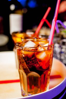 Bar arka planında bir bardak buzlu kokteyl. Siyah arka planda Bokeh ışığı olan camlı bir Wiskey. Bir bardak viski. Barın arka planında bir bardak viski ve buz..