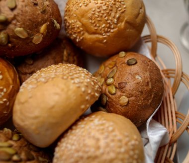 Kepekli, fındıklı ve susamlı çörekler. Sepette ekmek var. Taze pişmiş tahıllı ekmeği yulaf, fındık ve tohumla birlikte. Tam tahıllı çörek. Yakın plan fotoğraf. yumuşak odak