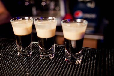 Bar arka planında bir bardak buzlu kokteyl. Siyah arka planda ışık olan cam bir Wiskey. Bir bardak viski. Barın arka planında bir bardak viski ve buz. kırmızı alkollü kokteyl.