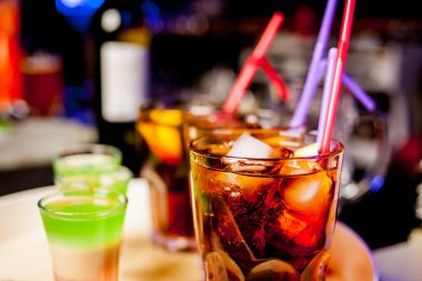 Bar arka planında bir bardak buzlu kokteyl. Siyah arka planda Bokeh ışığı olan camlı bir Wiskey. Bir bardak viski. Barın arka planında bir bardak viski ve buz..