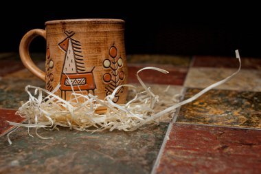 Kil kahverengi kupa, desenli kupalar, fayansın üzerinde dur. Şablonlu kilden kupa. Siyah arkaplanda boyanmış kil bardak. 