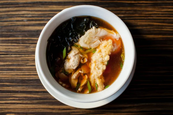 Geleneksel çorba udonu, beyaz tabakta, masada. Japon çorbasının adı Udon, kızarmış karides veya tempura. Erişte ve karidesli çorba. Orijinal Japon çorbası.
