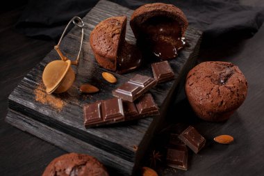 Çikolatalı ev yapımı kekler, çikolatalar ve siyah ahşap arka planda badem taneleri. Aşçı mutfakta çikolatalı kek hazırlar. Aşçı barda çikolatalı kek hazırlar..