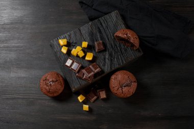 Çikolatalı ev yapımı kekler, çikolatalar ve siyah ahşap arka planda badem taneleri. Aşçı mutfakta çikolatalı kek hazırlar. Aşçı barda çikolatalı kek hazırlar..