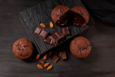 Çikolatalı ev yapımı kekler, çikolatalar ve siyah ahşap arka planda badem taneleri. Aşçı mutfakta çikolatalı kek hazırlar. Aşçı barda çikolatalı kek hazırlar..