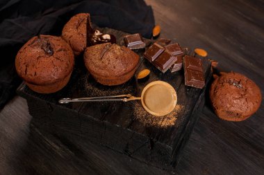 Çikolatalı ev yapımı kekler, çikolatalar ve siyah ahşap arka planda badem taneleri. Aşçı mutfakta çikolatalı kek hazırlar. Aşçı barda çikolatalı kek hazırlar..