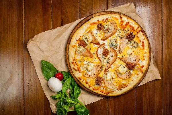 Kahverengi ahşap bir masada armut, ceviz ve gorgonzola ile ev yapımı pizza. El yapımı kağıt..