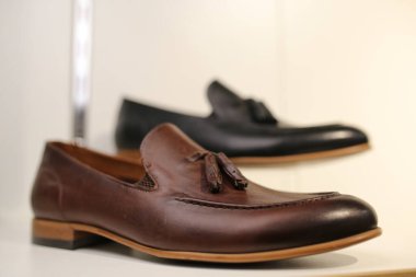 Şık bir deri, mağazadaki rafta emzirilmiş erkek ayakkabıları. Kürsüde siyah, kahverengi erkek ayakkabıları var. Erkek tarzı, moda. Damadın toplantıları. Rafta siyah, kahverengi deri erkek ayakkabıları var.