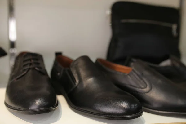 Stylish leather, lacquered mens shoes on the shelf in the store. Black, brown mens shoes on the stand. Male style, fashion. Gatherings of the groom. Mens shoes of black, brown leather on the shelf
