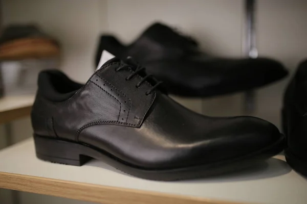 Stylish leather, lacquered mens shoes on the shelf in the store. Black, brown mens shoes on the stand. Male style, fashion. Gatherings of the groom. Mens shoes of black, brown leather on the shelf