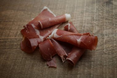 Ahşap arka planda dilimlenmiş jamon. Parma jambonu, ahşap arka planda jamon ve metin üst görüntüsü için yer var. Jamon Serrano, Iberico. Geleneksel İspanyol jambonu