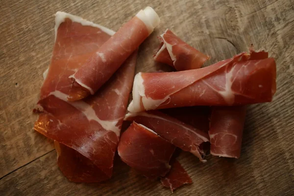 Ahşap arka planda dilimlenmiş jamon. Parma jambonu, ahşap arka planda jamon ve metin üst görüntüsü için yer var. Jamon Serrano, Iberico. Geleneksel İspanyol jambonu