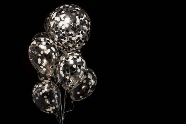 Black and white balloons on a dark black background. Celebration concept , White and black balloons on a dark black background for a holiday, birthday or other holiday. Photo for posters or postcards.