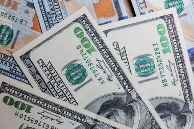 Önünde ve arkasında 100 dolarlık banknotlar var. Gelir, yatırım, başarılı iş. Amerikan dolarlarının yakın plan çekimleri, Amerikan dolarlarının arka plan dokusu