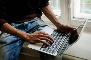 Bilgisayarda çalışan genç bir adam. İş yeri. Serbest meslek kavramı. Başarılı bir programcı. Dizüstü bilgisayarda çalışan bir iş adamının yakın çekimi. Bir adamın elindeki dizüstü bilgisayarın en üst görüntüsü