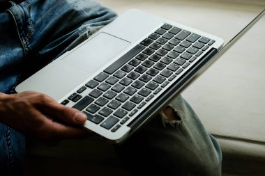 Bilgisayarda çalışan genç bir adam. İş yeri. Serbest meslek kavramı. Başarılı bir programcı. Dizüstü bilgisayarda çalışan bir iş adamının yakın çekimi. Bir adamın elindeki dizüstü bilgisayarın en üst görüntüsü