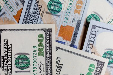 Önünde ve arkasında 100 dolarlık banknotlar var. Gelir, yatırım, başarılı iş. Amerikan dolarlarının yakın plan çekimleri, Amerikan dolarlarının arka plan dokusu