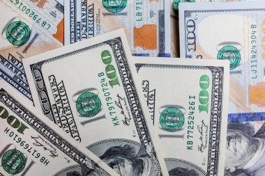 Önünde ve arkasında 100 dolarlık banknotlar var. Gelir, yatırım, başarılı iş. Amerikan dolarlarının yakın plan çekimleri, Amerikan dolarlarının arka plan dokusu