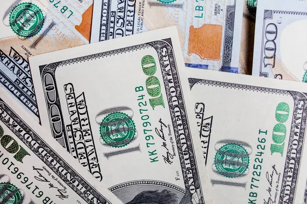 Önünde ve arkasında 100 dolarlık banknotlar var. Gelir, yatırım, başarılı iş. Amerikan dolarlarının yakın plan çekimleri, Amerikan dolarlarının arka plan dokusu