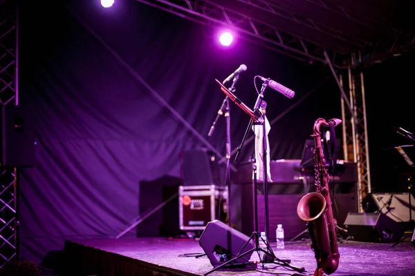 Saxophone Instrument on the Stage, photo close-up. Golden saxophone stands on the stage next to other musical instruments.