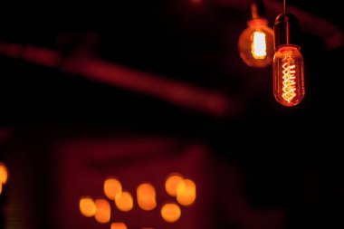 Siyah arka planda Edison lambası. Bokeh ile koyu arkaplanı olan parlak bir ampul. Tungsten lambaları sıcaklığı hissettirir. Retro Edison ampulü, alışılmadık bir spiralle, Bokeh ile