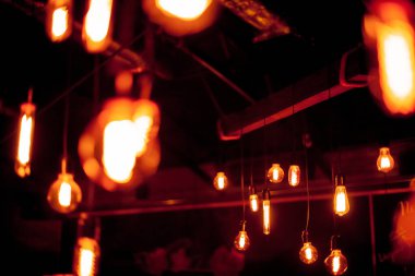 Siyah arka planda Edison lambası. Bokeh ile koyu arkaplanı olan parlak bir ampul. Tungsten lambaları sıcaklığı hissettirir. Retro Edison ampulü, alışılmadık bir spiralle, Bokeh ile