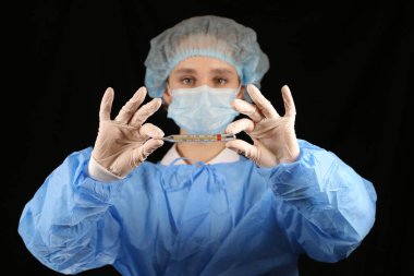 Bir hemşire, maskeli bir virüs uzmanı termometre tutuyor. 2021 salgını. Coronavirüs 'ü durdurun. COVID-19. Viral, koronavirüs aşısı. Karantinaya alın. Avrupa 'da koronavirüs, dünya. sıcaklık taraması