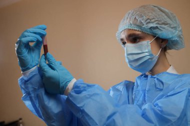 Bir hemşire, Çin, Wuhan 'dan alınmış koronavirüs pozitif kan örneği içeren bir test tüpü tutuyor. 2019 nCoV salgını. Coronavirüs 'ü durdurun. MERS. Bir virüs uzmanı koronavirüs aşısı düşünüyor. Grip, kuş gribi.