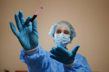 Bir hemşire, Çin, Wuhan 'dan alınmış koronavirüs pozitif kan örneği içeren bir test tüpü tutuyor. 2019 nCoV salgını. Coronavirüs 'ü durdurun. MERS. Bir virüs uzmanı koronavirüs aşısı düşünüyor. Grip, kuş gribi.