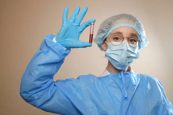 Koruyucu maskeli ve gözlüklü bir doktor elinde Coronavirus için pozitif kan örneği olan bir test tüpü tutuyor. Coronavirüs 'ü durdurun. MERS. COVID-19. 2021 Salgını.