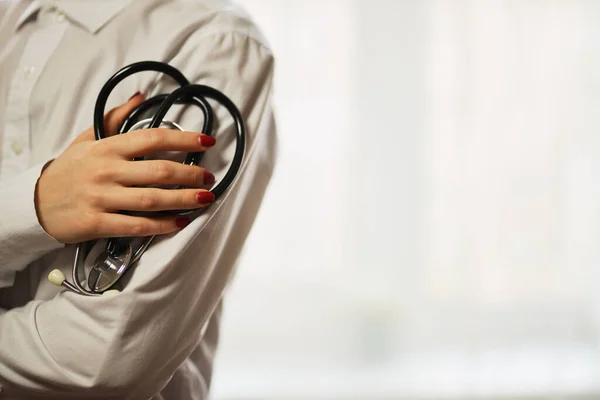 doctor with a stethoscope on hospital background. A doctor in a white coat with a stethoscope. coronavirus treatment. A doctor in a white coat holds a stethoscope in his hands. Healthcare concept.