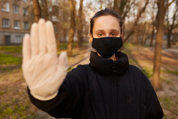 Dziewczyna Czarnej Kurtce Czarnej Masce Medycznej Pokazuje Ręką Znak Stop — Zdjęcie stockowe