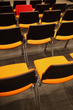 Siyah ve turuncu plastik konferans sandalyeleri. Konferans odasında siyah ve turuncu sandalyeler. Siyah ve turuncu sandalyelerin arka planı.