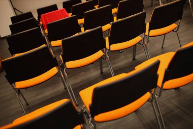 Siyah ve turuncu plastik konferans sandalyeleri. Konferans odasında siyah ve turuncu sandalyeler. Siyah ve turuncu sandalyelerin arka planı.