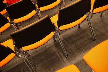 Siyah ve turuncu plastik konferans sandalyeleri. Konferans odasında siyah ve turuncu sandalyeler. Siyah ve turuncu sandalyelerin arka planı.