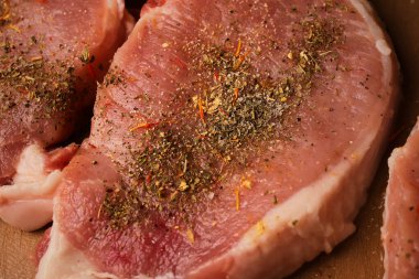 Kesme tahtasındaki dana biftek. Plastik kesim tahtasında baharatlı dana biftek. Baharatlı çiğ biftek. Yakın plan fotoğraf. Kesme tahtasındaki çiğ biftek..