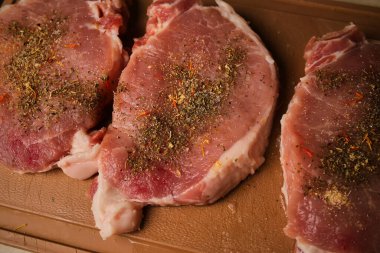 Kesme tahtasındaki dana biftek. Plastik kesim tahtasında baharatlı dana biftek. Baharatlı çiğ biftek. Yakın plan fotoğraf. Kesme tahtasındaki çiğ biftek..