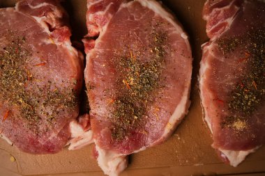 veal steak on a cutting board. veal steak with spices on a plastic cutting board. 
