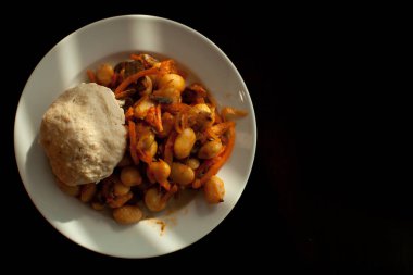 Siyah arka planda beyaz tabakta sebzeli fasulye ve tavuk pirzolası. Sebzeli fasulye. Sebzeli fasulye. Yakın plan, güveç tipik İspanyol, Türk fasulyesi