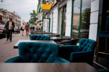 Interior of a summer open-air cafe. summer outdoor cafe terrace. Street cafe. Cozy outdoor restaurant. Suede emerald armchairs