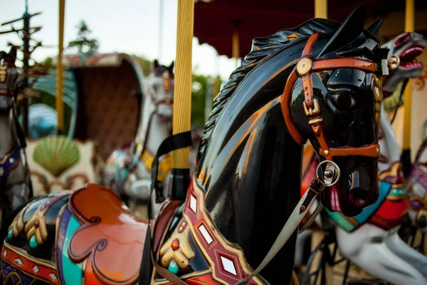 Retro carousel white, black horse. Old wooden horse carousel. Carousel Horses on vintage, retro carnival cheerful walk. CloseUp of colorful carousel with horses.