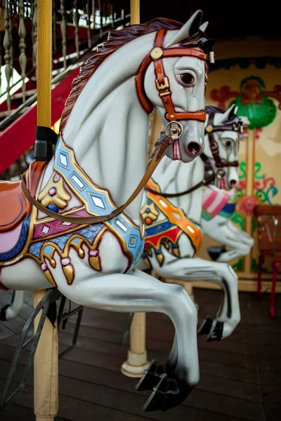 Retro carousel white, black horse. Old wooden horse carousel. Carousel Horses on vintage, retro carnival cheerful walk. CloseUp of colorful carousel with horses.