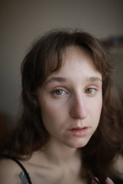 Mavi bluz giymiş üzgün, kahverengi saçlı, beyaz bir kadın. 