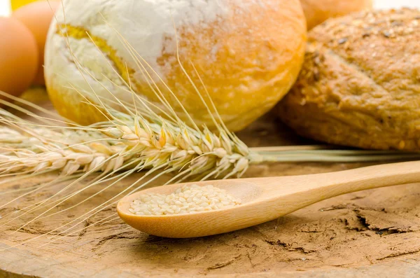 Pane fresco e grano sul legno — Foto Stock